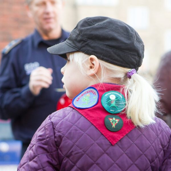 To spejderledere viser en færdselstavle for en gruppe børn